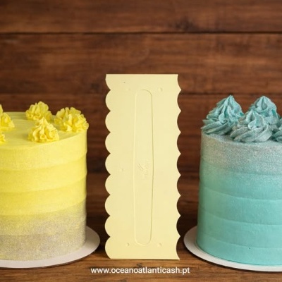 Dois bolos decorados amarelo e azul com espátula creme ao centro sobre mesa rústica