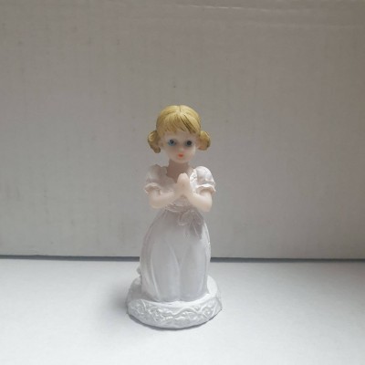Estatueta de criança loira a rezar com vestido branco em fundo neutro