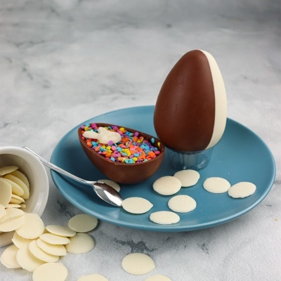 Ovos de Páscoa de chocolate com confeites coloridos e pastilhas de chocolate branco num prato azul