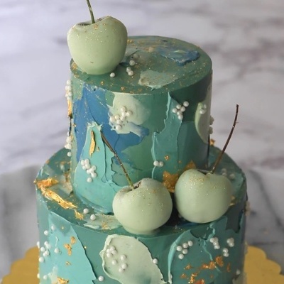 Bolo duas camadas verde azul com cerejas brilhantes e pérolas brancas