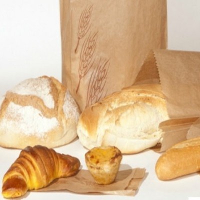 variedade de pães e pastel de nata sobre papel castanho com saco de papel ao fundo