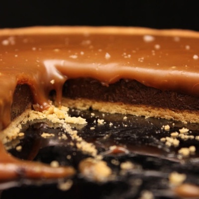 Sobremesa com camada de chocolate, bolo escuro e base crocante.