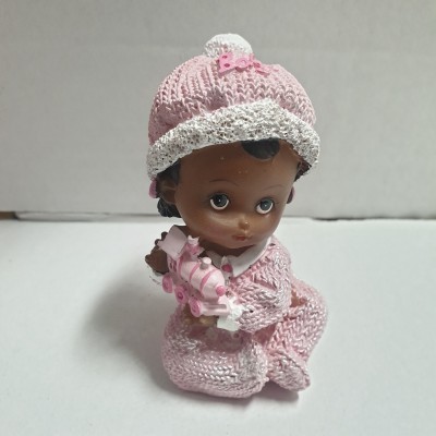 Boneca de bebé com roupa de malha rosa segurando brinquedo em fundo cinzento
