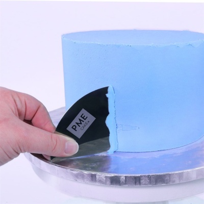 Bolo com cobertura azul clara sendo alisado com espátula preta PME CAKES