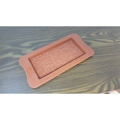 Forma de silicone castanha clara com padrão geométrico em relevo sobre superfície de madeira