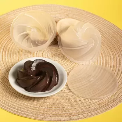 moldes de silicone transparentes em espiral com bolo de chocolate num prato branco sobre base trançada