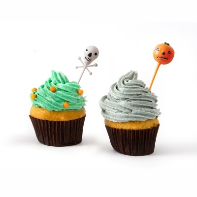 Dois cupcakes decorados para Halloween com coberturas verde e cinza e toppers de crânio e abóbora.