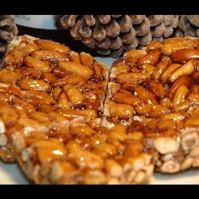 Barras de amendoins caramelizados em prato com pinhas ao fundo