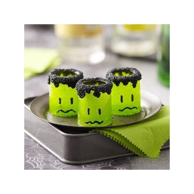 Três pequenos copos verdes com rostos tristes e bordas pretas num prato metálico