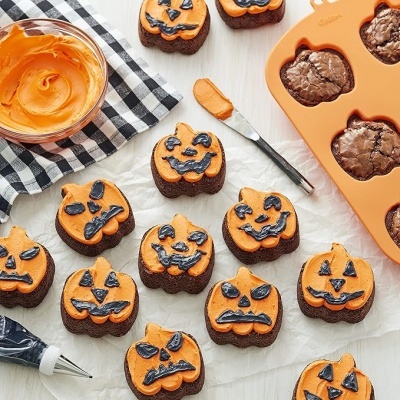 Bolinhos decorados em forma de abóbora de Halloween com glacê laranja e preto