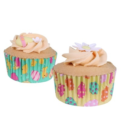 Dois cupcakes com creme salmão e embalagens coloridas com desenhos de ovos e bolinhas.