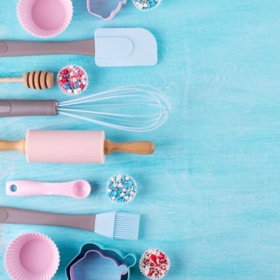 Utensílios de cozinha rosa e cinza sobre fundo azul