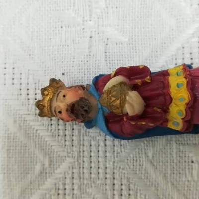 Estatueta colorida de figura humana com coroa dourada