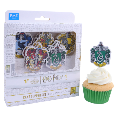 Conjunto de cake toppers Harry Potter com brasões das casas em embalagem, junto a cupcake verde com cobertura branca.
