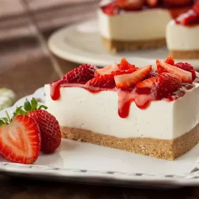 Fatias de cheesecake com morangos e base de bolacha em prato branco