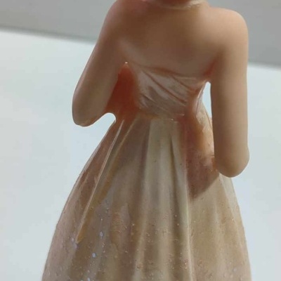 Estatueta de mulher com vestido longo creme e cabelo castanho apanhado