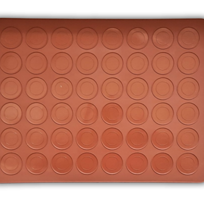 Forma de silicone com cavidades redondas cor de tijolo sobre fundo preto