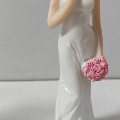 Estatueta decorativa de mulher com vestido branco e flores rosas em suporte branco crescente