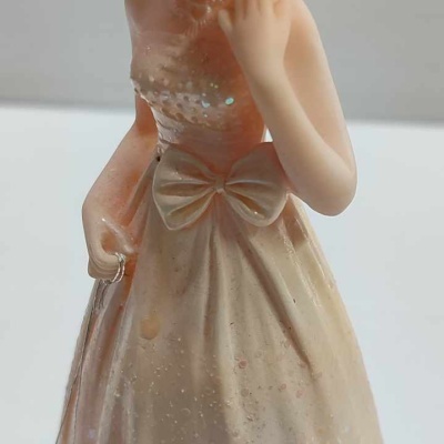Figura decorativa de mulher com vestido longo creme e cabelo apanhado