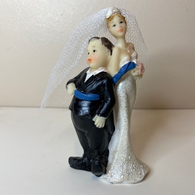 Figuras decorativas de noivos para bolo em cerâmica com véu branco.