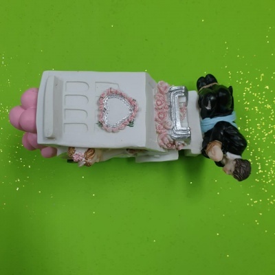 Figura decorativa de casamento com noivos e carro branco com detalhes cor-de-rosa