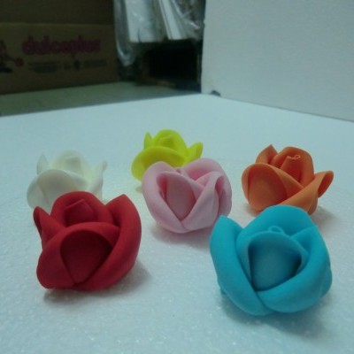 Seis flores decorativas de várias cores em superfície branca texturizada.