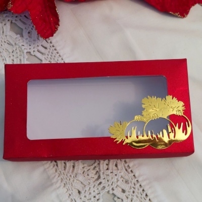 Caixa vermelha com tampa transparente decorada com bolas de Natal douradas e folhas