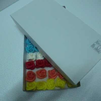 Caixa branca com pequenas flores de tecido de várias cores dentro