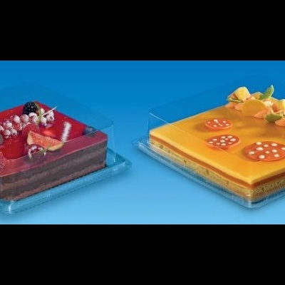 Dois bolos quadrados em bases plásticas, um vermelho com chocolate e frutas, outro amarelo com flores e frutas, fundo azul.
