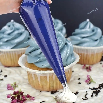 Cupcakes com cobertura azul e saco de confeitar azul aplicando cobertura branca.