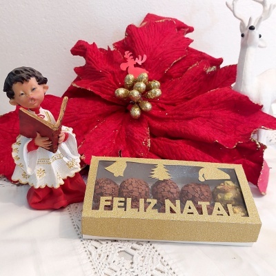 Caixa de chocolates com tampa dourada 'FELIZ NATAL' e decoração natalícia
