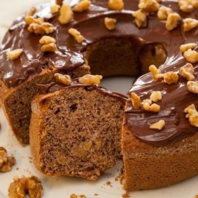 Bolo com cobertura de chocolate e nozes num prato branco