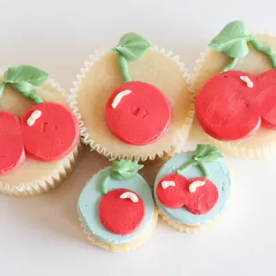 Cupcakes decorados com cerejas vermelhas e folhas verdes