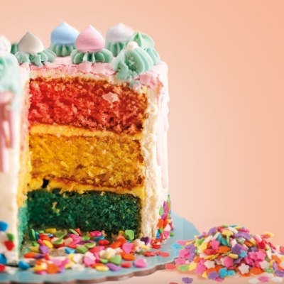 Bolo colorido de três camadas com chantilly e corações coloridos.