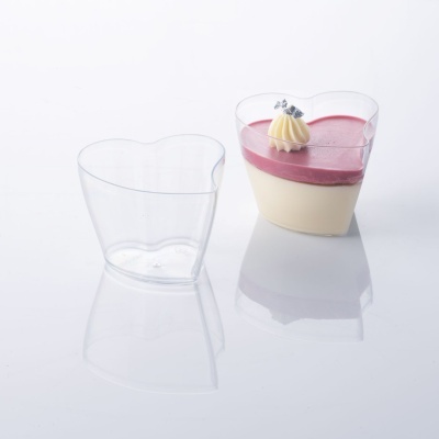 Copos plásticos em forma de coração com sobremesa cremosa rosa e creme