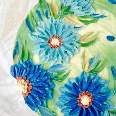 Detalhe de bolo decorado com flores em glacê azul e verde