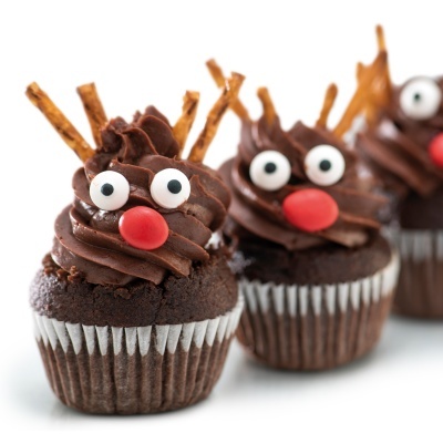 Cupcakes de chocolate decorados com creme de chocolate, olhos de açúcar, nariz vermelho e palitos de pretzel como chifres.