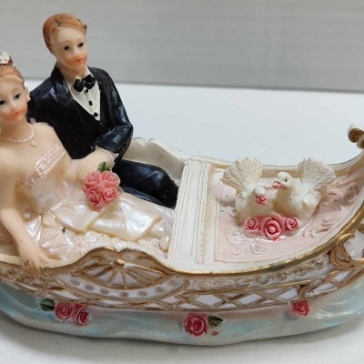 Escultura decorativa de noivos numa gôndola com pombos e flores