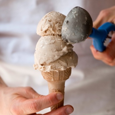 Cone de gelado com duas bolas bege claro e colher azul