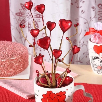 Bolo rosado e objetos decorativos com corações vermelhos em copos brancos