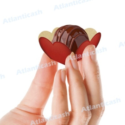 Bombom de chocolate em embalagem de coração segurado por dedos.