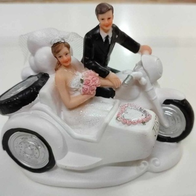 Figuras decorativas de noivos sentados numa mota branca com sidecar