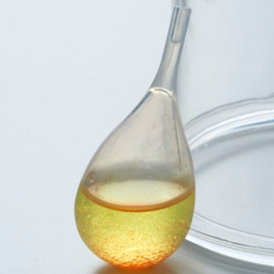 Recipiente em vidro translúcido em forma de gota com líquido amarelo e base laranja