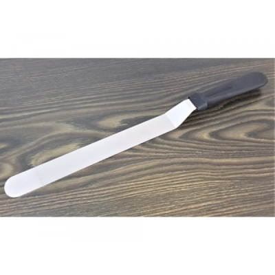 Espátula metálica com cabo preto em superfície de madeira escura