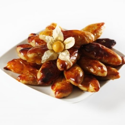 Prato branco com doze pães doces caramelizados e physalis no centro