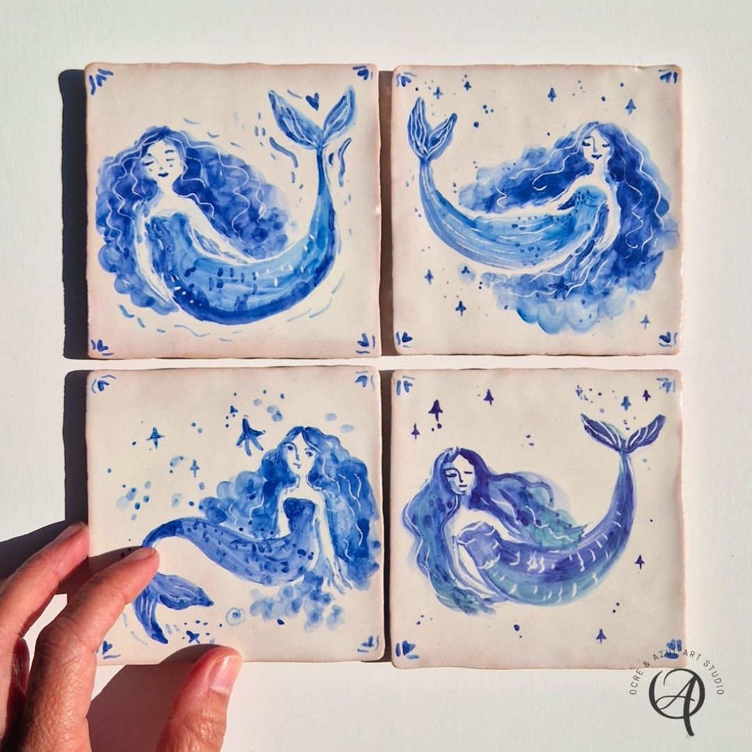 Azulejo coleção Sereias Conjunto de quatro azulejos quadrados com desenhos azuis de sereias sobre fundo branco.