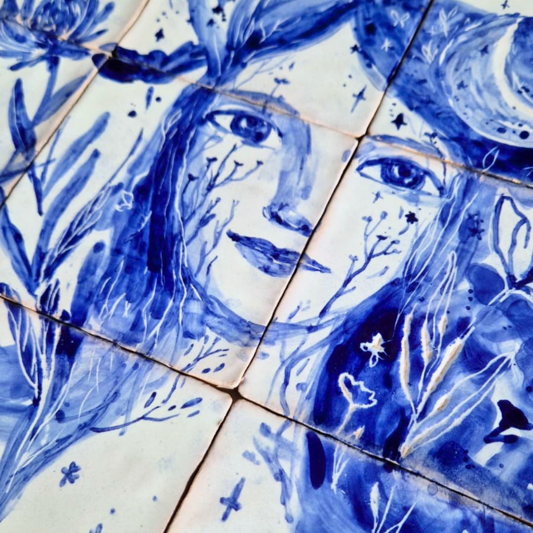 Painel de azulejos Sinfonia azul II Azulejos azuis e brancos com pintura de rosto feminino e elementos florais.