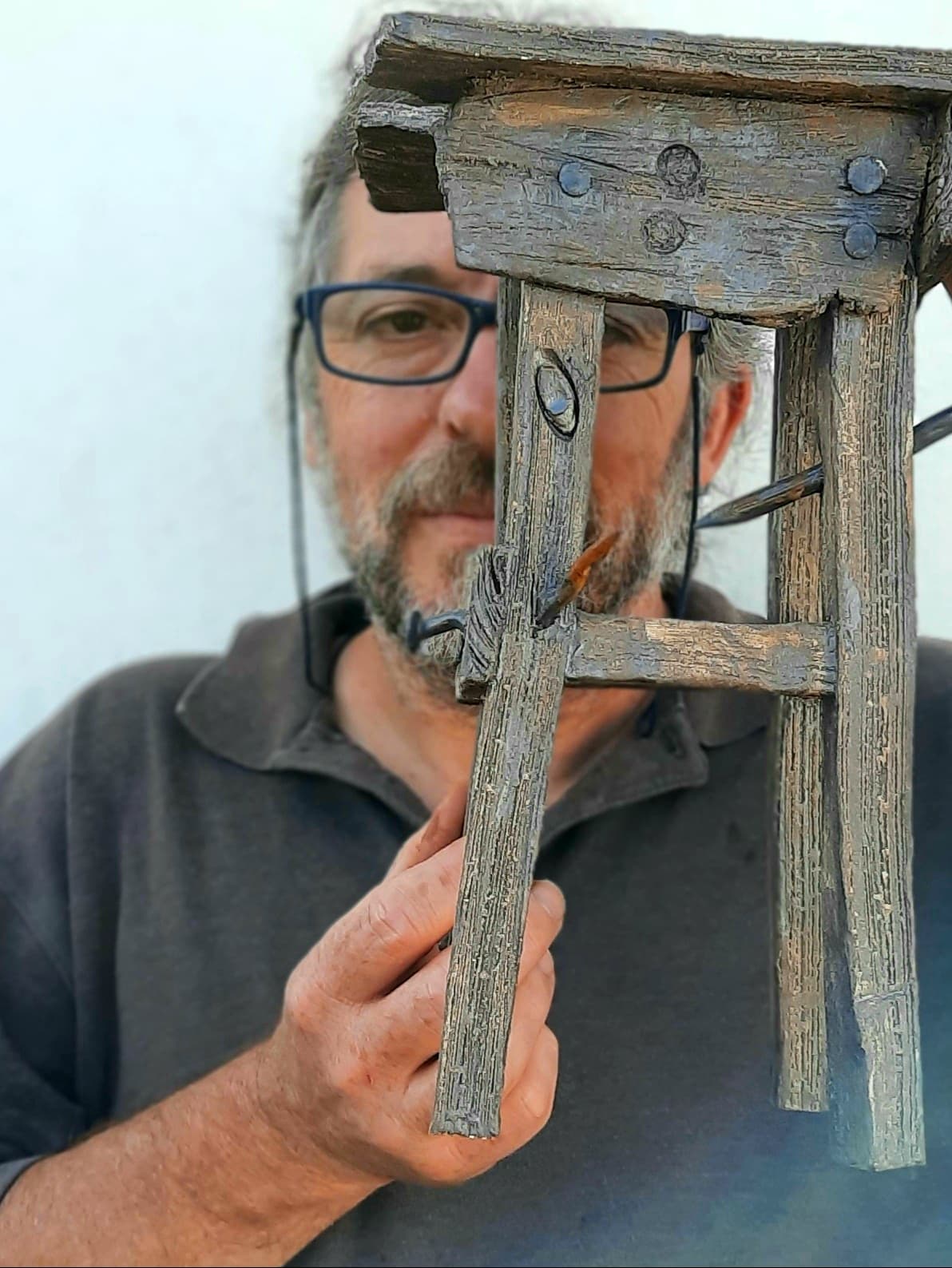 João, a ligação à Terra e Natureza. Banco de madeira rústico cinzento segurado por homem com óculos