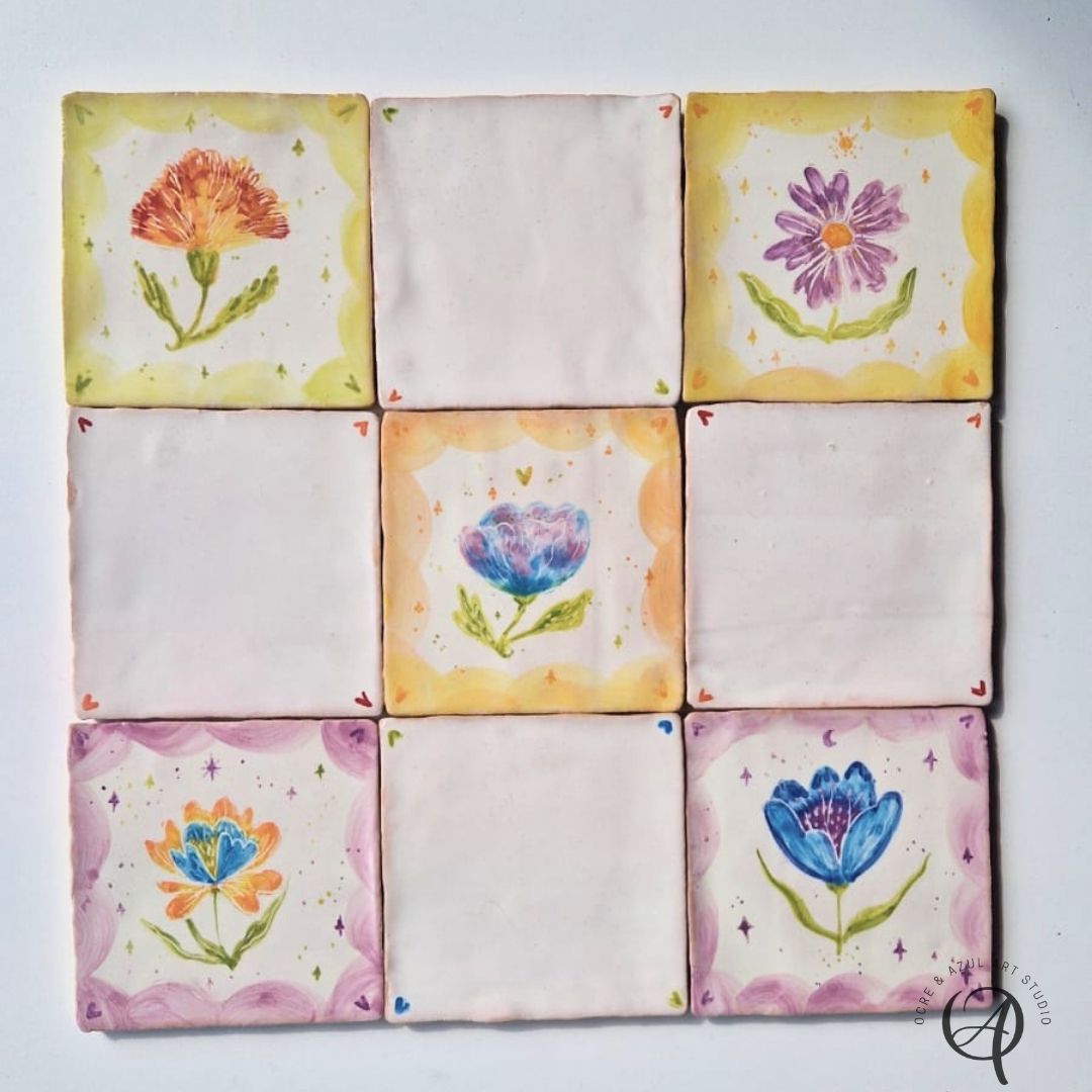 Azulejo Mix Colorido Azulejos quadrados com flores pintadas e bordas coloridas em superfície branca.
