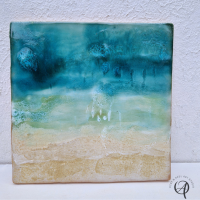 Azulejo decorativo com padrão abstrato em tons de azul, verde e bege.